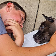 Ronnie joined the competition — help win amazing prizes! boy, dog, face, paw, arm, concrete, blanket, curious, closeup, interaction, pet, child, outdoor, animal, friendship, laying_down, expression, human, companion, trust