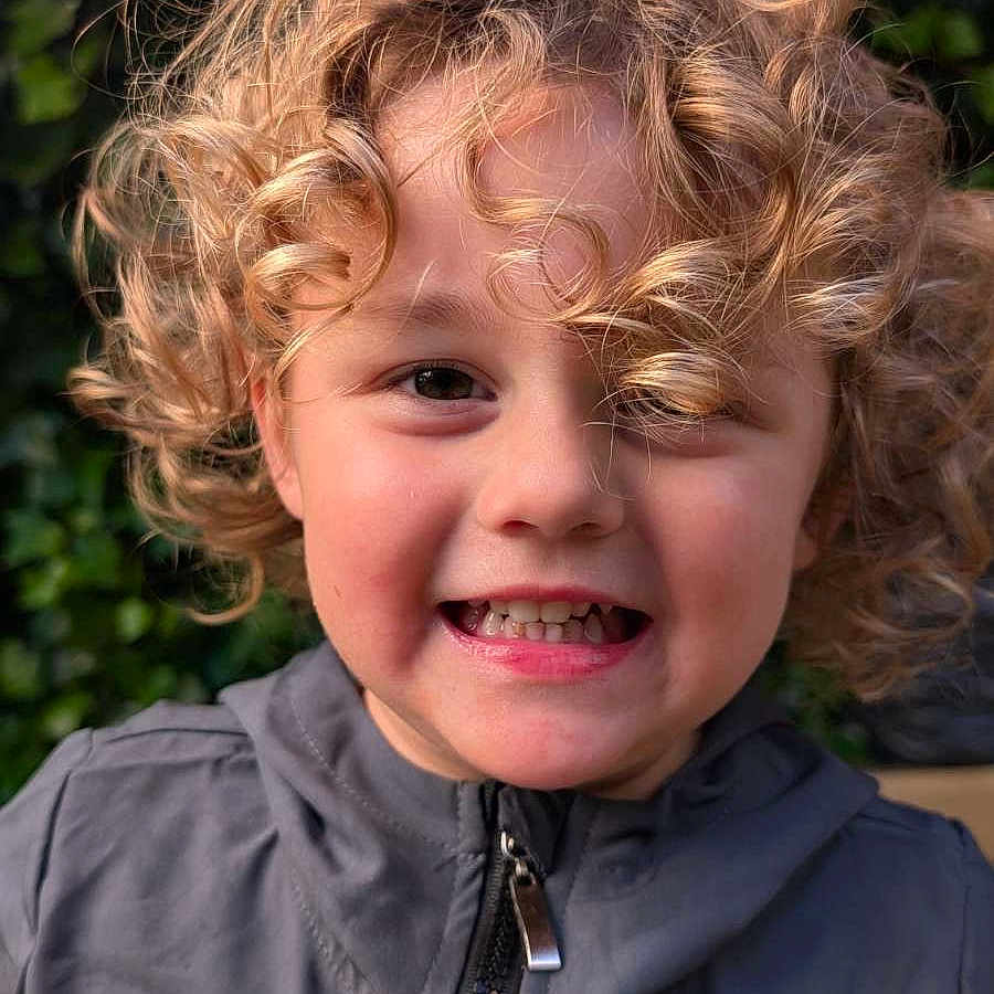 Alessyo a rejoint le concours — aidez-le/la à gagner de superbes lots ! casual_clothing, child, childhood, closeup, curly_hair, cute, daylight, expression, eyes, face, greenery, happy, jacket, nature, outdoor, person, portrait, skin, smile, young