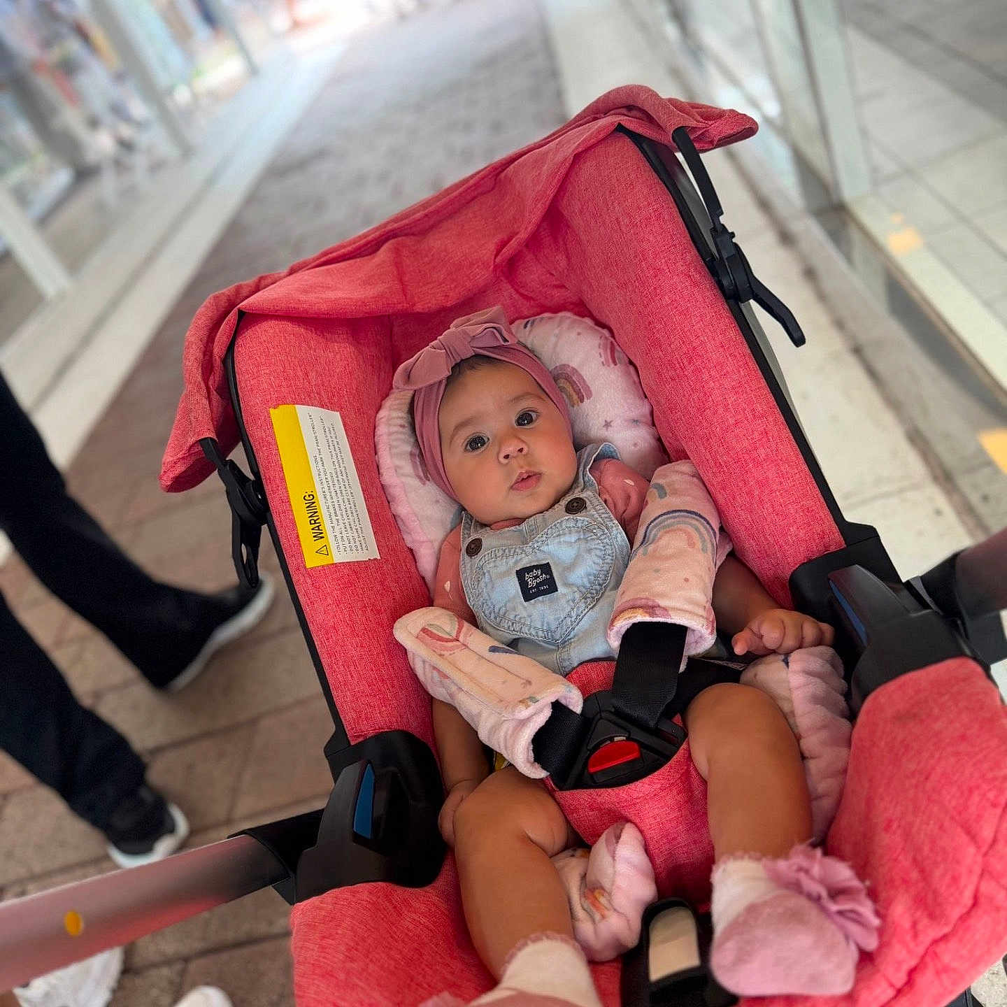 Kimberly joined the competition — help win amazing prizes! baby, stroller, pink, child, infant, clothing, headband, footwear, urban, sidewalk, people, blurred_background, seated, safety_harness, cute, portrait, shopping_area, casual, daytime, outdoor