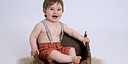 Julian participe au concours pour gagner de l'argent avec cette photo : baby, child, smile, suspenders, shorts, wooden_bed, furry_rug, happy, portrait, studio, light_background, cute, sitting, bare_chest, infant, small_bed, feet, hands, face, expression