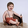 baby, child, smile, suspenders, shorts, wooden_bed, furry_rug, happy, portrait, studio, light_background, cute, sitting, bare_chest, infant, small_bed, feet, hands, face, expression