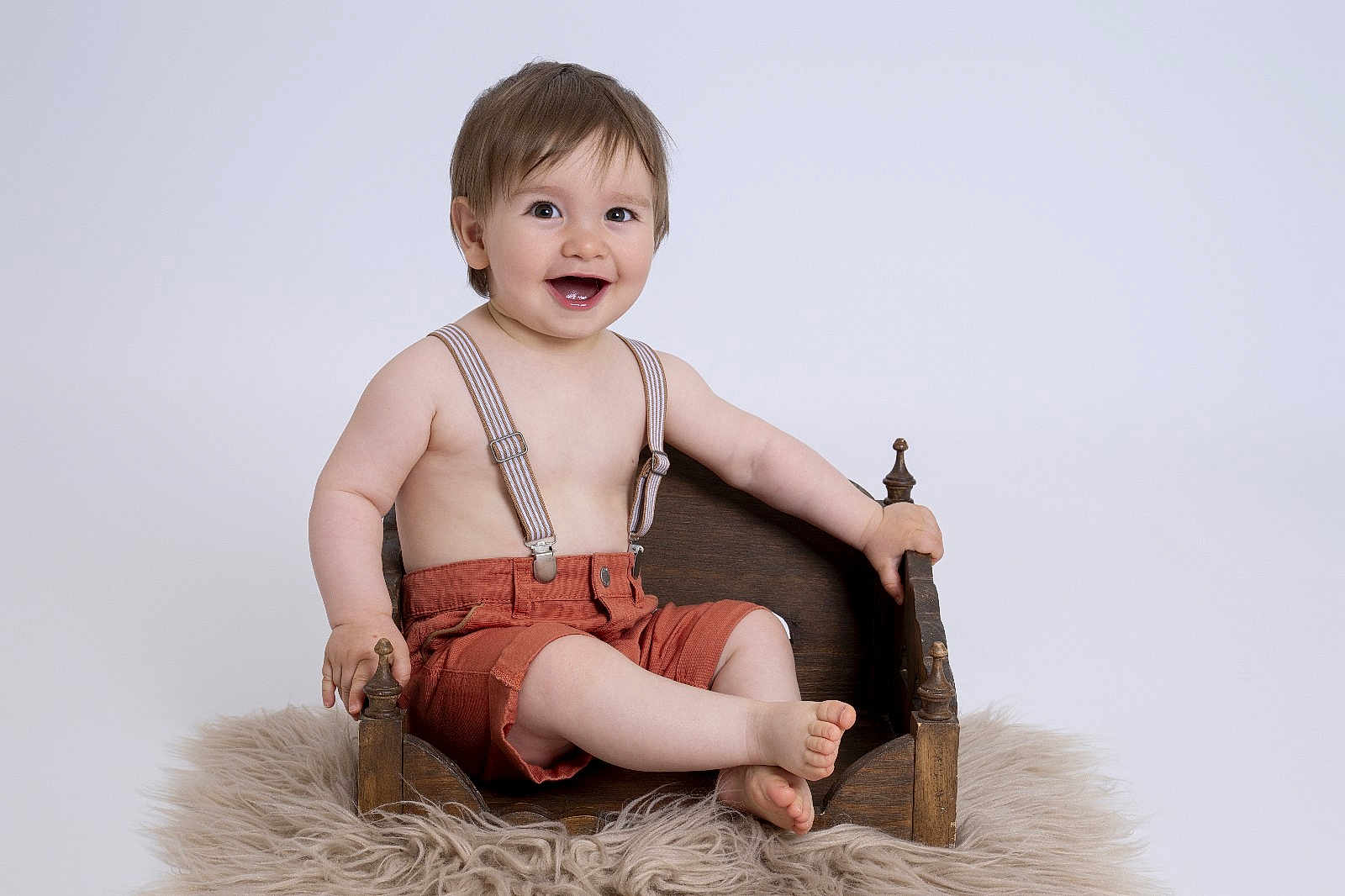 Julian participe au concours pour gagner de l'argent avec cette photo : baby, child, smile, suspenders, shorts, wooden_bed, furry_rug, happy, portrait, studio, light_background, cute, sitting, bare_chest, infant, small_bed, feet, hands, face, expression