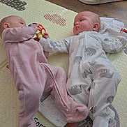 Zoey joined the competition — help win amazing prizes! baby, baby_toys, child, colorful_toy, crawling_mat, cute, floor, footwear, hand_holding, indoor, infant, interaction, lying_down, onesie, pink_clothing, play_mat, playtime, toy, white_clothing, wood_floor