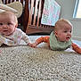 baby, bib, carpet, crib, cute, floor, holding_hands, home, indoor, infant, long_sleeves, playful, portrait, quilt, sibling, sunlight, tummy_time, two_babies, window, wooden_crib