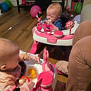 Zoey is registered to the contest to win money with this photo: baby, babies, infant, baby_walker, toy, toys, pink, minnie_mouse, mickey_mouse_toy, playtime, wooden_floor, living_room, balloon, shelf, adult_leg, seat, snack, hand, mirror, feeding_baby
