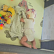 Zoey joined the competition — help win amazing prizes! baby, blanket, child, childcare, colorful, comfort, floor, helmet, home, indoors, infant, lying_down, play_mat, playpen, protection, resting, soft_toy, striped_clothing, toy, wood_floor