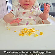 Zoey is registered to the contest to win money with this photo: baby, child, curious, expression, face, feeding, food, foot, furniture, hands, helmet, high_chair, home, indoor, meal_time, onesie, protective_gear, scrambled_eggs, toddler, wood_floor
