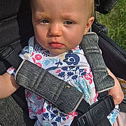 Chloe is registered to the contest to win money with this photo: baby, casual_wear, child, clothing, cute, daylight, floral_shirt, grass, infant, outdoor, person, pink_pants, portrait, safety_harness, seat, seatbelt, serious_expression, stroller, sunlight, young_child