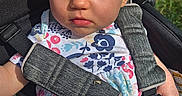 Chloe is registered to the contest to win money with this photo: baby, casual_wear, child, clothing, cute, daylight, floral_shirt, grass, infant, outdoor, person, pink_pants, portrait, safety_harness, seat, seatbelt, serious_expression, stroller, sunlight, young_child