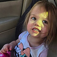 Alaina is registered to the contest to win money with this photo: child, toddler, seatbelt, car_interior, window, sunlight, smile, teeth, long_hair, pink_clothing, hand, portrait, candid, seat, shirt, toy, safety, young_child, backseat, cute