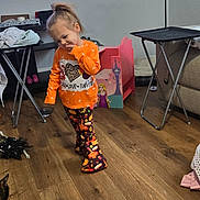 Alaina is registered to the contest to win money with this photo: child, toddler, orange_shirt, patterned_pants, wooden_floor, living_room, floor_lamp, toy_box, television, slipper, cat, furniture, home, cute_pose, indoor, casual_clothing, floor, smiling, person, cozy