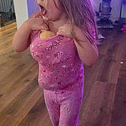 Alaina joined the competition — help win amazing prizes! child, girl, pajamas, pink, snack, barefoot, wooden_floor, vacuum_cleaner, indoor, home, person, standing, long_hair, purple_lighting, casual, candid, floor, legs, feet, toy