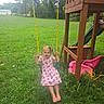 child, girl, swing, playground, grass, outdoor, dress, pigtails, barefoot, toy, slide, wood, greenery, summer, daytime, recreation, backyard, yellow_chain, pink, playset