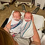 Chloe And Zoey is registered to the contest to win money with this photo: newborn, twins, baby, hospital, swaddled, medical_tubes, person, lap, floor, hospital_equipment, blanket, sleeping, infant, healthcare, patient, footwear, tattoo, arm, hospital_room, bed