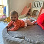 baby, smiling, indoor, child, playground, slide, orange_clothing, gray_cushion, happy, floor, window, toy, play_area, light, crawling, person, home, childhood, cute, infant