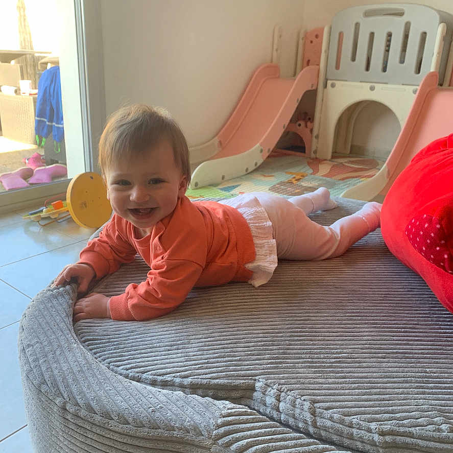 Ambre a rejoint le concours — aidez-le/la à gagner de superbes lots ! baby, child, childhood, crawling, cute, floor, gray_cushion, happy, home, indoor, infant, light, orange_clothing, person, play_area, playground, slide, smiling, toy, window