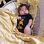 baby, black_clothing, blanket, child, cozy, cushion, cute, face, headband, indoor, infant, leopard_print, lying_down, newborn, onesie, person, portrait, soft_texture, winnie_the_pooh, yellow