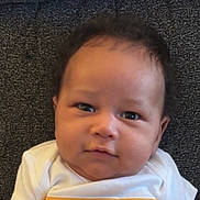 Lukas joined the competition — help win amazing prizes! baby, cheeks, child, close_up, curious, dark_background, eyes, face, hair, head, indoors, infant, person, photography, portrait, serious, shirt, sitting, textured_background, white_clothing
