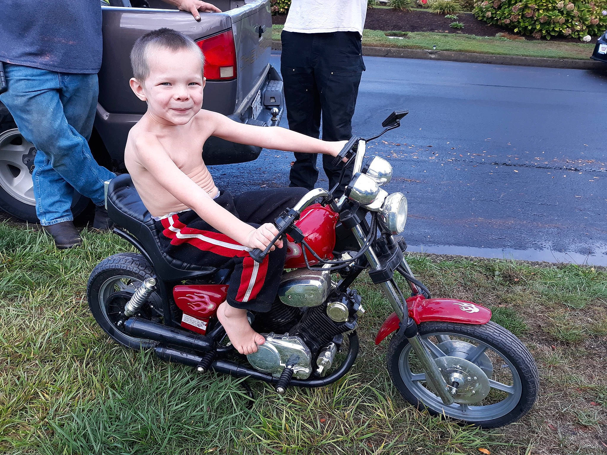 Danny is registered to the contest to win money with this photo: alloy_wheel, automotive_design, automotive_exterior, automotive_lighting, automotive_tire, fender, fuel_tank, grass, joy, leg, motor_vehicle, motorcycle, motorcycle_accessories, person, plant, rim, shoe, sneakers, tire, vehicle