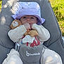 baby, purple_hat, teddy_bear, plush_toy, baby_chair, outdoor, grass, sunlight, infant, cute, child, soft_toys, blanket, smiling, person, nature, daylight, relaxing, comfort, clothing