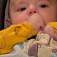 Aimé a rejoint le concours — aidez-le/la à gagner de superbes lots ! animal_pattern, baby, blanket, child, closeup, comfort, cozy, cute, eyes, face, hand, indoors, infant, portrait, skin, sleepy, soft_texture, thumb, warm, yellow_clothing