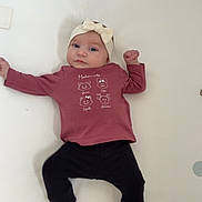 Albane participe au concours pour gagner de l'argent avec cette photo : baby, black_pants, blanket, child, clothing, cozy, cute, dots, expression, face, hands_up, headband, indoors, infant, lying_down, pink_shirt, portrait, small_footwear, white_socks, young_child
