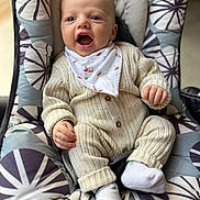 Rafaël a rejoint le concours — aidez-le/la à gagner de superbes lots ! baby, infant, child, smiling, knitwear, bib, socks, baby_seat, cushion, patterned_fabric, cozy, cute, happy, indoors, portrait, person, small_hands, open_mouth, seated, comfort
