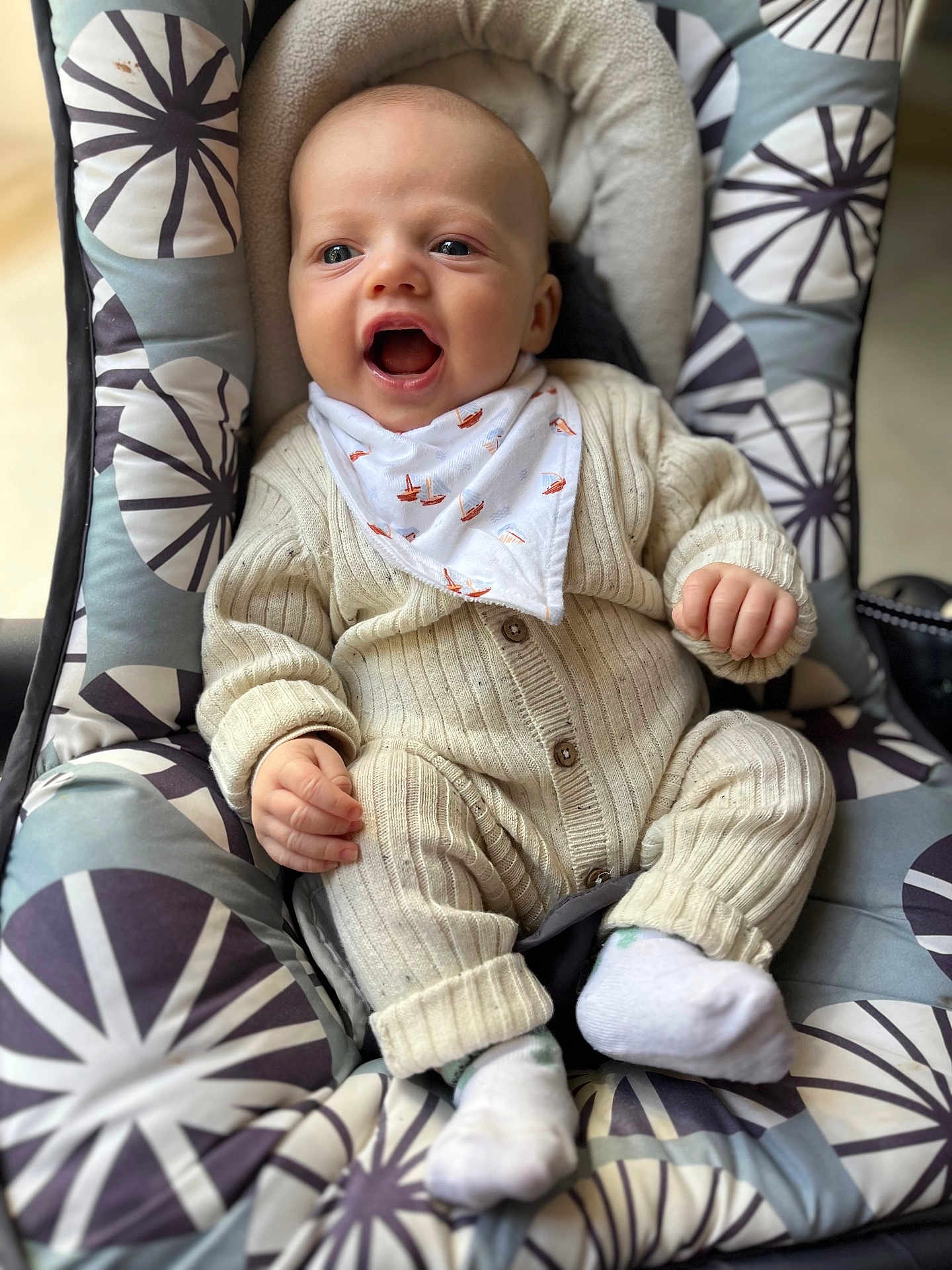 Rafaël a rejoint le concours — aidez-le/la à gagner de superbes lots ! baby, infant, child, smiling, knitwear, bib, socks, baby_seat, cushion, patterned_fabric, cozy, cute, happy, indoors, portrait, person, small_hands, open_mouth, seated, comfort