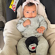 Ella participe au concours pour gagner de l'argent avec cette photo : baby, car_seat, headband, grey_clothing, socks, infant, child, seatbelt, comfort, indoors, cute, expression, safety, soft, cozy, person, young_child, face, hands, resting