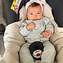baby, car_seat, headband, grey_clothing, socks, infant, child, seatbelt, comfort, indoors, cute, expression, safety, soft, cozy, person, young_child, face, hands, resting