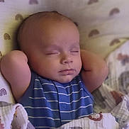 Miles is registered to the contest to win money with this photo: baby, sleeping, blanket, blue_clothing, infant, peaceful, arms_up, cozy, face, head, soft_lighting, patterned_blanket, indoors, resting, child, portrait, cute, newborn, calm, relaxed
