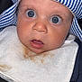 Beau-Harley is registered to the contest to win money with this photo: baby, child, blue_eyes, striped_hat, bib, stain, close_up, face, infant, curious, wide_eyes, clothing, portrait, cute, expression, person, headwear, newborn, apparel, seatbelt
