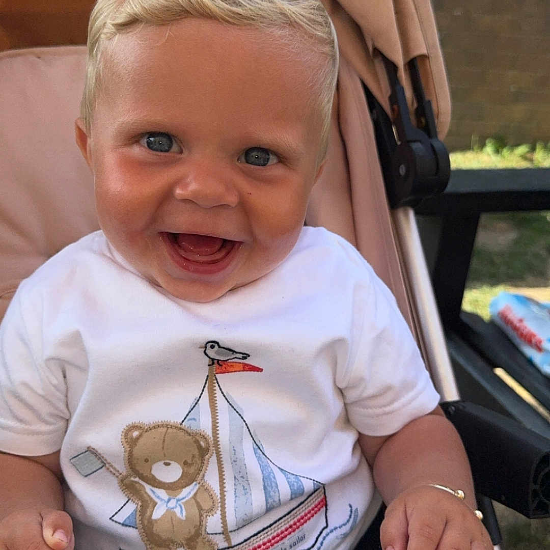 Beau-Harley joined the competition — help win amazing prizes! baby, blanket, blue_eyes, child, clothing, cute, face, hand, happy, infant, nature, outdoor, portrait, sailboat, seatbelt, smiling, stroller, sunlight, teddy_bear, white_shirt