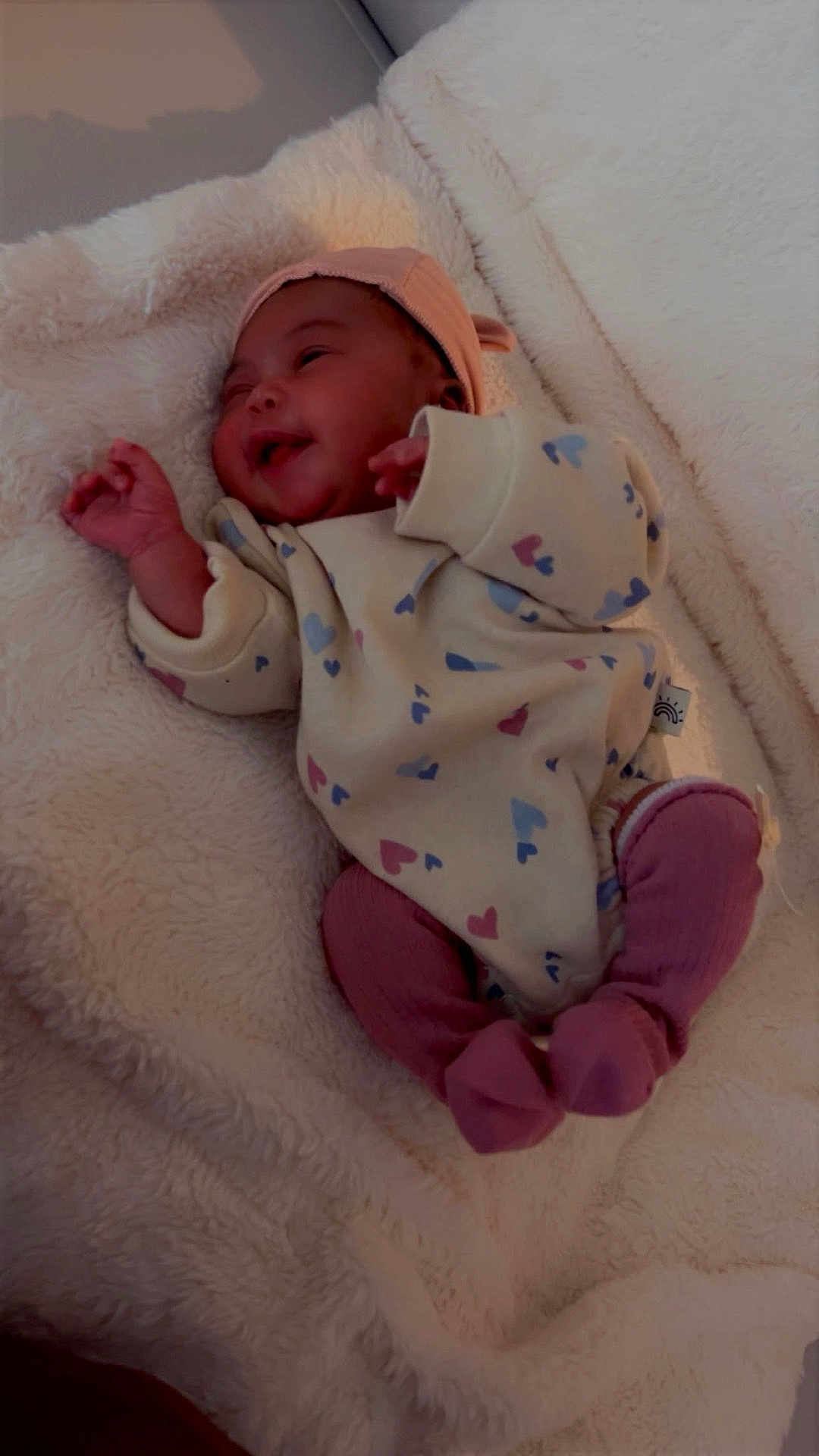 Zirachi is registered to the contest to win money with this photo: baby, infant, smile, heart_pattern, onesie, pink_socks, blanket, cozy, soft_texture, lying_down, cute, happy, child, newborn, warm, indoors, sleepwear, headwear, small_hands, resting
