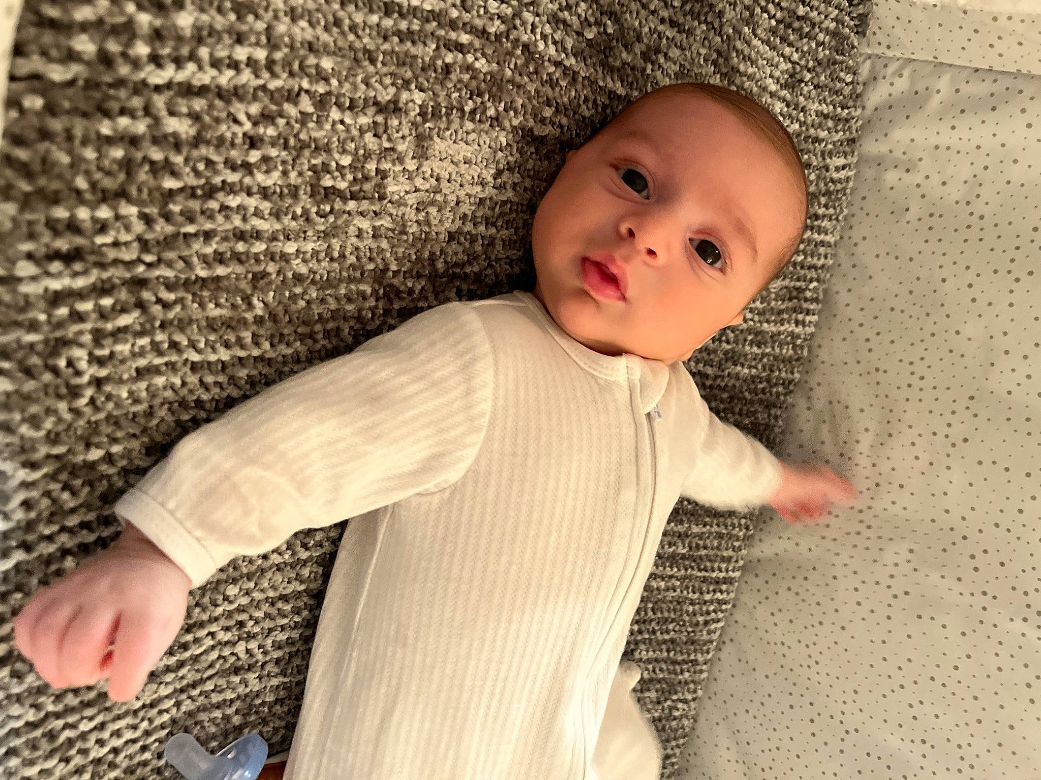 Nikko is registered to the contest to win money with this photo: baby, baby_toddler_clothing, child, comfort, finger, flooring, gesture, headwear, linens, monochrome, pattern, person, sitting, skin, sleeve, textile, thumb, toddler, wood, wool