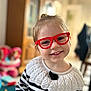 Aliya participe au concours pour gagner de l'argent avec cette photo : child, glasses, red_glasses, smile, happy, portrait, indoor, striped_sweater, knitwear, young_child, face, cute, person, fashion, hair_up, furniture, blurred_background, cozy, home, playroom