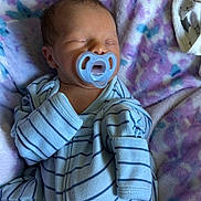 David is registered to the contest to win money with this photo: baby, newborn, pacifier, sleeping, striped_clothing, onesie, blanket, soft_texture, infant, face, closed_eyes, hand, resting, cozy, cute, child, portrait, indoor, sleep, peaceful