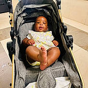 Anaya is registered to the contest to win money with this photo: baby, stroller, indoor, floor, tile, child, person, foot, clothing, fabric, blanket, seat, handle, playful, cute, infant, relaxing, modern, expression, kicking