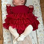 baby, infant, red_dress, white_tights, changing_pad, animal_print, floor, wooden_floor, cute, child, looking_sideways, indoor, small_hands, small_feet, tulle, ruffles, soft_lighting, laying_down, adorable, young_child