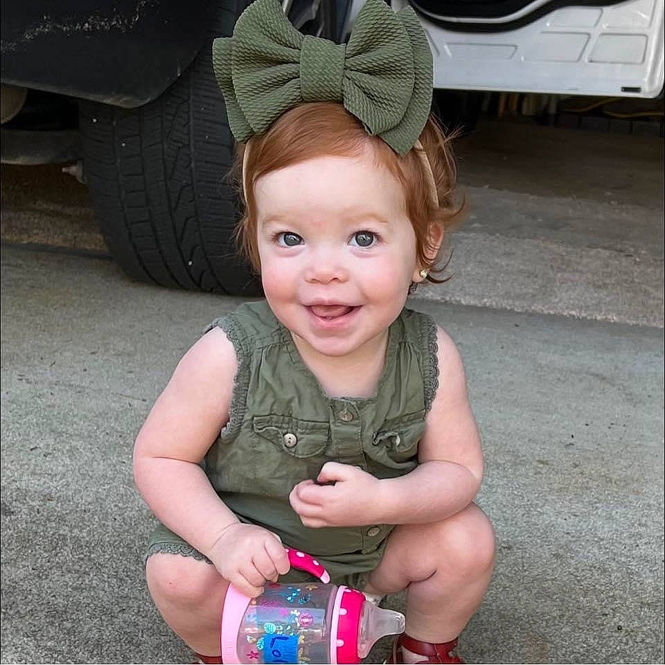 Lola is registered to the contest to win money with this photo: automotive_exterior, automotive_tire, baby, baby_toddler_clothing, fender, fun, hair, happy, head, iris, joy, person, pink, rim, skin, smile, thumb, tire, toddler, tread