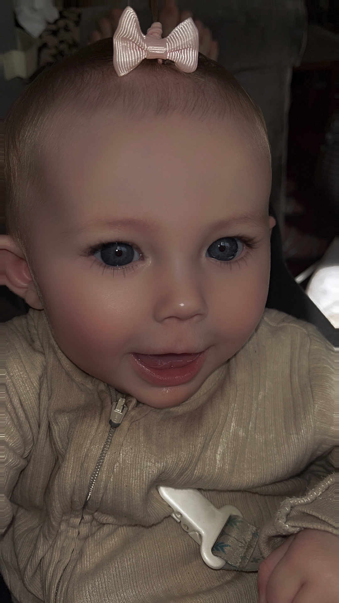 Sienna-Grace joined the competition — help win amazing prizes! baby, child, infant, face, blue_eyes, bow, clothing, zipper, pacifier_clip, hand, indoor, portrait, cute, smile, skin, head, young, person, closeup, happy