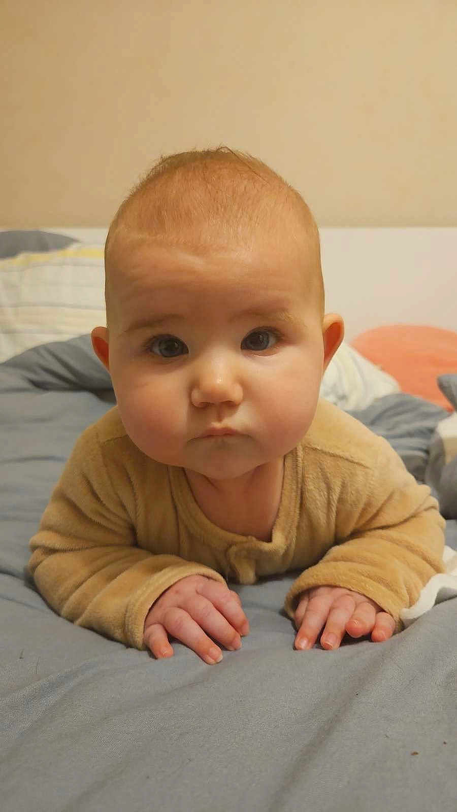 Alix a rejoint le concours — aidez-le/la à gagner de superbes lots ! baby, child, face, hands, bed, bedding, blanket, pajamas, tummy, curious, indoors, young_child, skin, person, cute, infant, soft, warm, sleepwear, expression