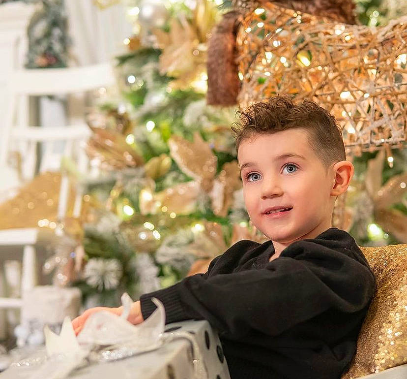 Luciano is registered to the contest to win money with this photo: christmas, christmas_decoration, christmas_eve, christmas_ornament, christmas_tree, conifer, event, fun, happy, holiday, holiday_ornament, ornament, people_in_nature, person, room, sitting, smile, toddler, tradition, winter