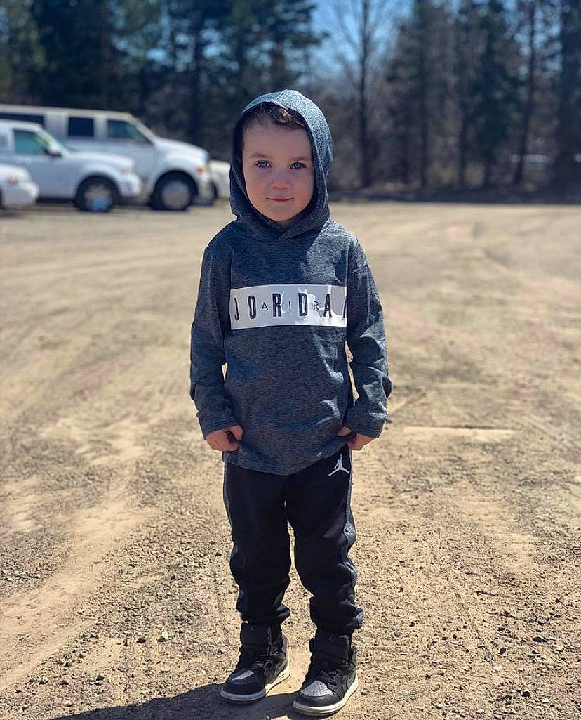 Luciano is registered to the contest to win money with this photo: asphalt, automotive_tire, car, grass, happy, headwear, landscape, mountainous_landforms, people_in_nature, person, personal_protective_equipment, recreation, sleeve, sportswear, street_fashion, t_shirt, tire, toddler, tree, vehicle