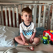 Kuiper is registered to the contest to win money with this photo: bandage, bed, checkered_pattern, child, crib, expression, face, fire_truck, furniture, healthcare, hospital, indoor, light, medical_equipment, medical_tube, person, sippy_cup, toddler, toy, white_shirt