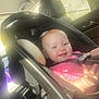 Lexi joined the competition — help win amazing prizes! baby, car_seat, child, smile, infant, pink_clothing, car_interior, sunlight, seatbelt, headrest, window, face, person, happy, safety, transportation, young_child, seat, vehicle, daylight