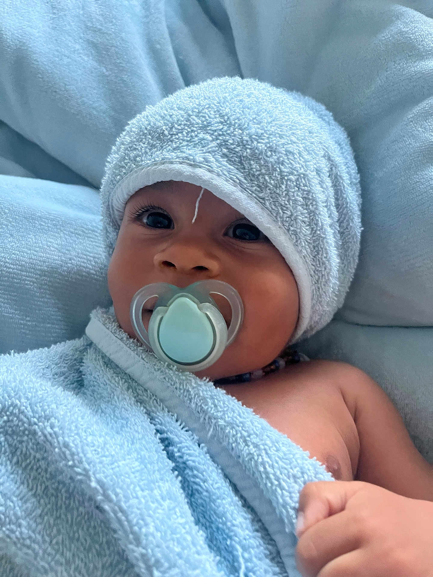 Connor a rejoint le concours — aidez-le/la à gagner de superbes lots ! baby, towel, pacifier, face, child, skin, hand, blue, soft, portrait, indoors, cute, wrapped, headwear, infant, expression, closeup, newborn, resting, relaxed