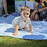 baby, child, toddler, crawling, outdoor, grass, blanket, gift_bags, people, adult, casual_clothing, sunlight, daylight, portrait, cute, summer, family, celebration, happy, event