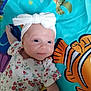 baby, infant, headband, bow, floral_clothing, blue_eyes, play_mat, colorful, fish, turtle, cute, lying_down, child, smile, patterned_clothing, soft_lighting, indoors, portrait, young_child, baby_girl