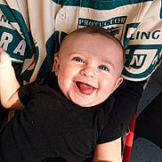 Viv joined the competition — help win amazing prizes! baby, child, smiling, happy, face, blue_eyes, black_shirt, person, holding, lap, patterned_clothing, green_color, white_color, indoors, infant, cute, joy, tongue_out, skin, human